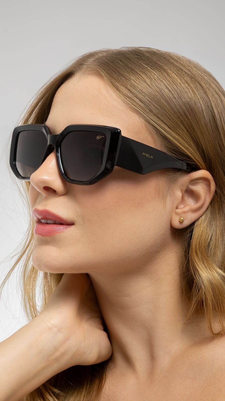 Óculos de sol preto com o emblema Anela na modelo.
